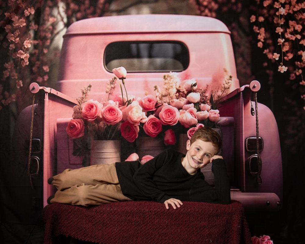 Pink cherry blossoms fall around a vintage pickup truck in a dreamy artistic photo series.