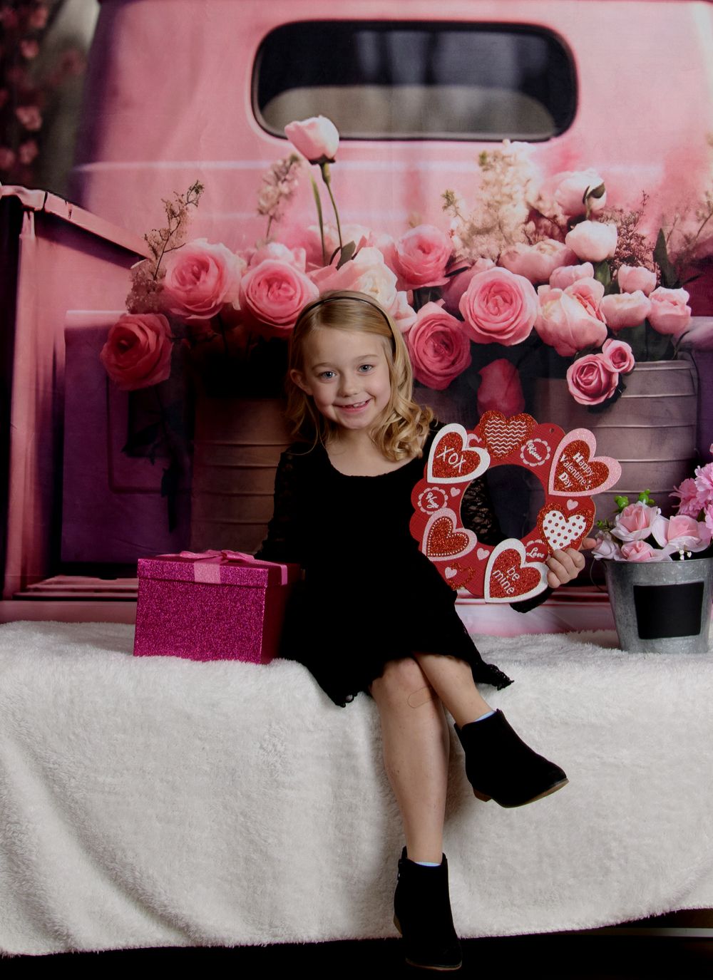 Pink roses and hearts create a romantic Valentine's Day themed photo session setup against a light background.