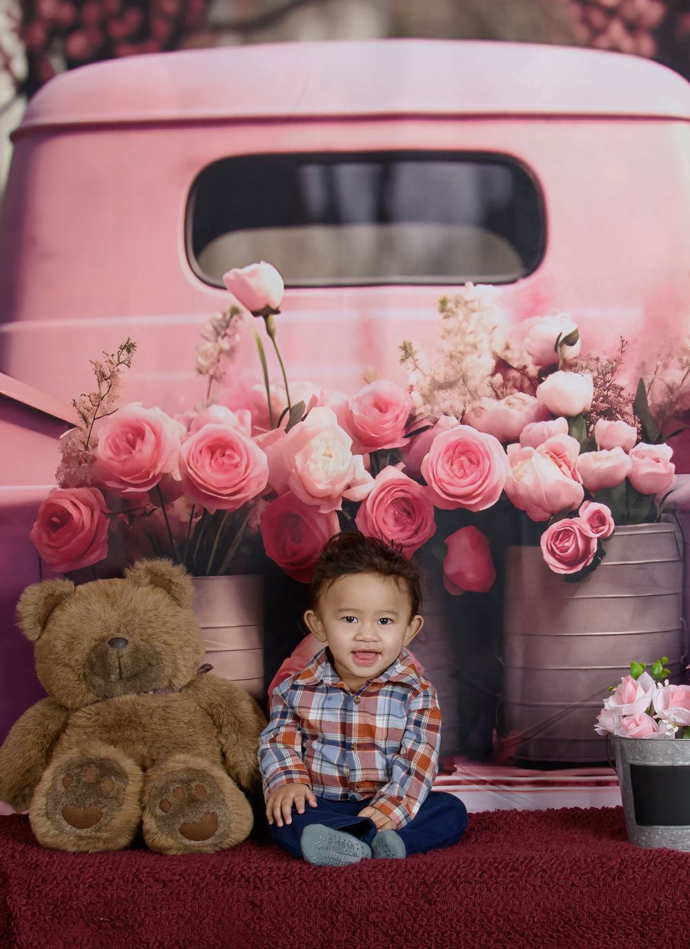Pink truck photo setup with plush teddy bear and beautiful pink roses arranged around the scene.
