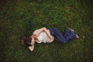 A series of artistic maternity photos taken lying in green grass at sunset.