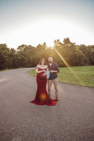 Romantic sunset photoshoot on a paved path wearing a flowing burgundy dress.