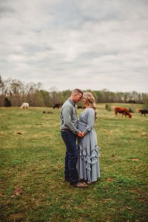 Intimate portrait of couple in pastoral setting with cattle grazing in background.
