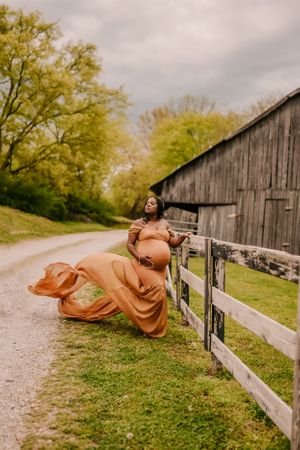 A flowing rust-colored dress billows dramatically against a rustic barn backdrop.