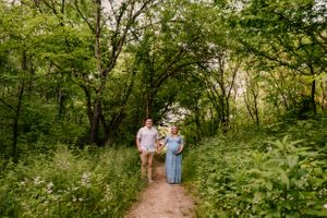 A couple walks along a tree-lined path during a romantic outdoor photoshoot.