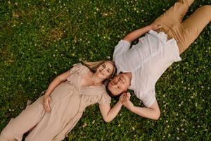 A couple lies in grass with yellow wildflowers during a romantic outdoor photoshoot.