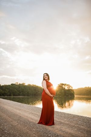 Glowing sunset maternity portrait by lakeside with warm golden light.