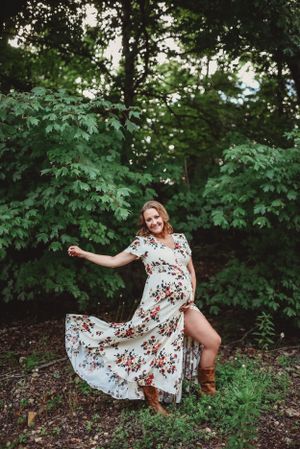 A twirling floral dress captures movement against lush green forest backdrop.
