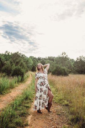 A flowing floral dress catches sunlight on a natural path through summer fields.