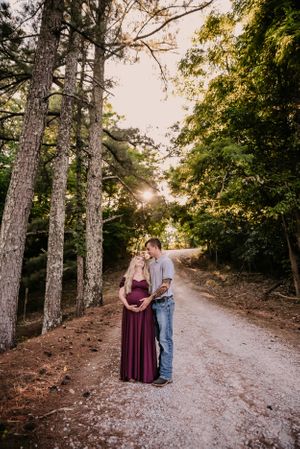 A couple strolls down a tree-lined path during golden hour creating romantic shadows.
