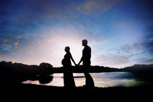 Silhouettes of people against a dramatic sunset sky create a peaceful scene.