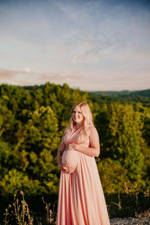 A maternity photo session captures glowing moments at sunset with rolling hills in the background.