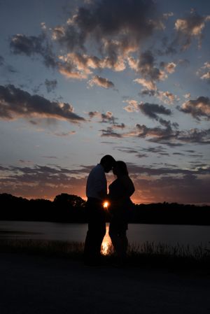 Romantic silhouettes against a vibrant sunset sky over a tranquil lake.