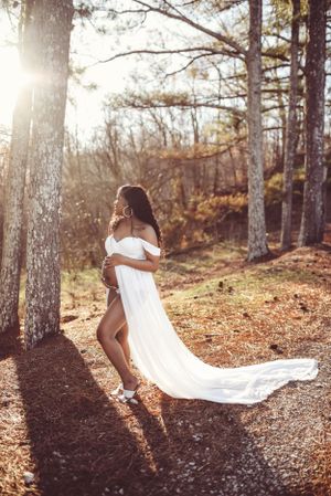 Sunlit forest photography session featuring flowing white fabric and natural lighting.