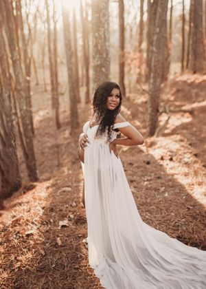 Ethereal forest photography featuring flowing white dress against sunlit woodland backdrop.