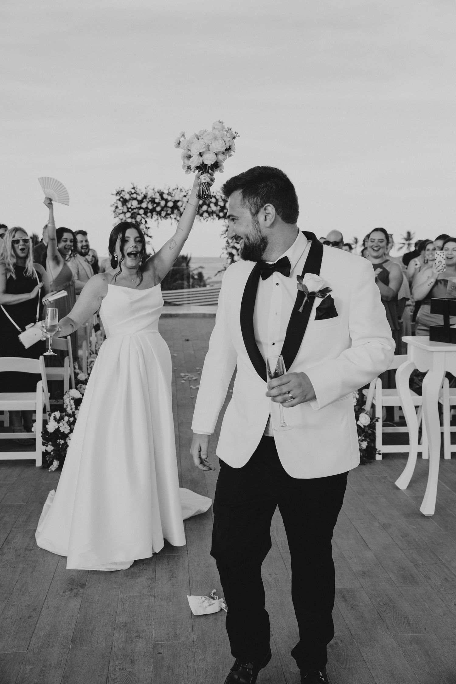 Black and white photo of wedding guests dancing during the reception on an outdoor dance floor.