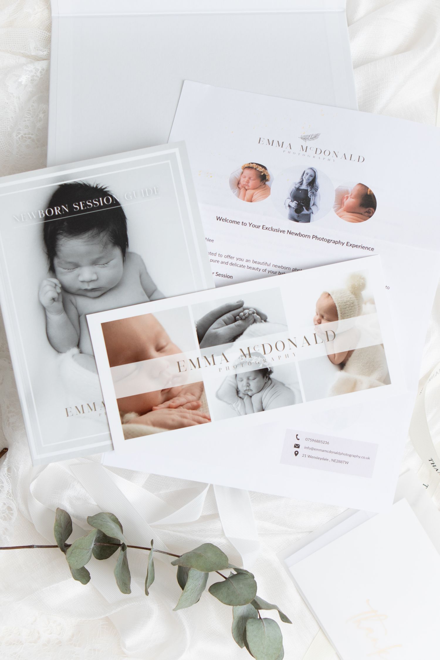 Professional photography business cards and prints displayed with soft white fabric and eucalyptus branch styling.