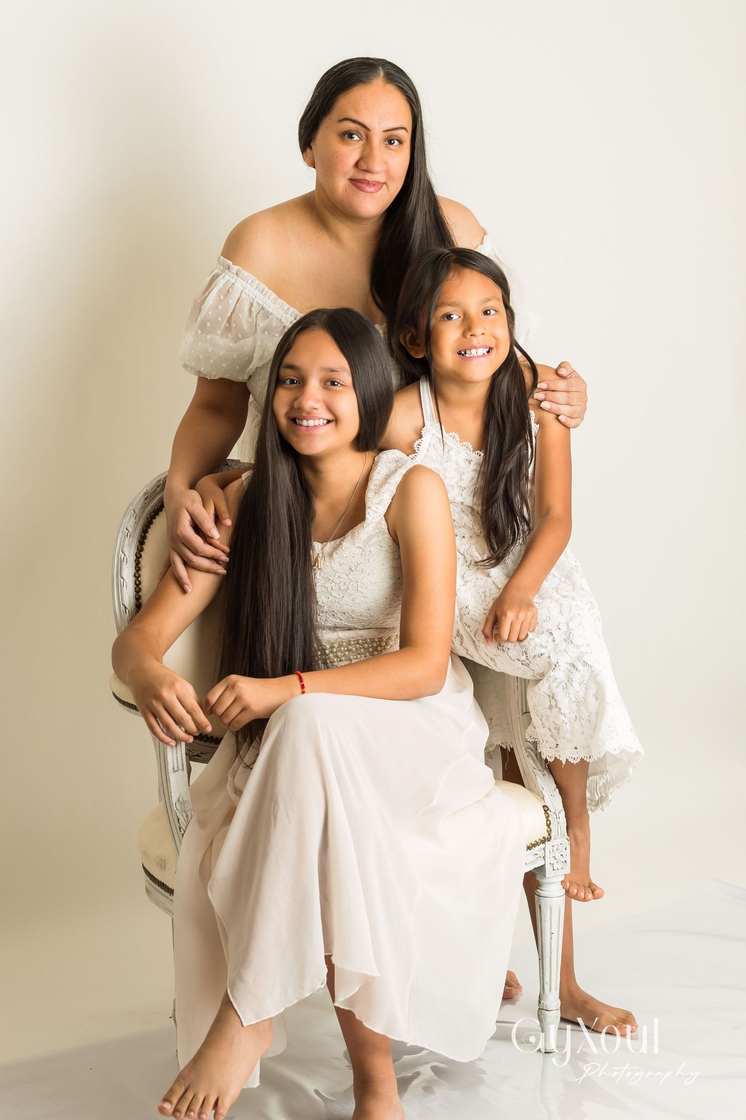 Two people wearing white dresses share intimate moments and smiles in a series of natural studio portraits.