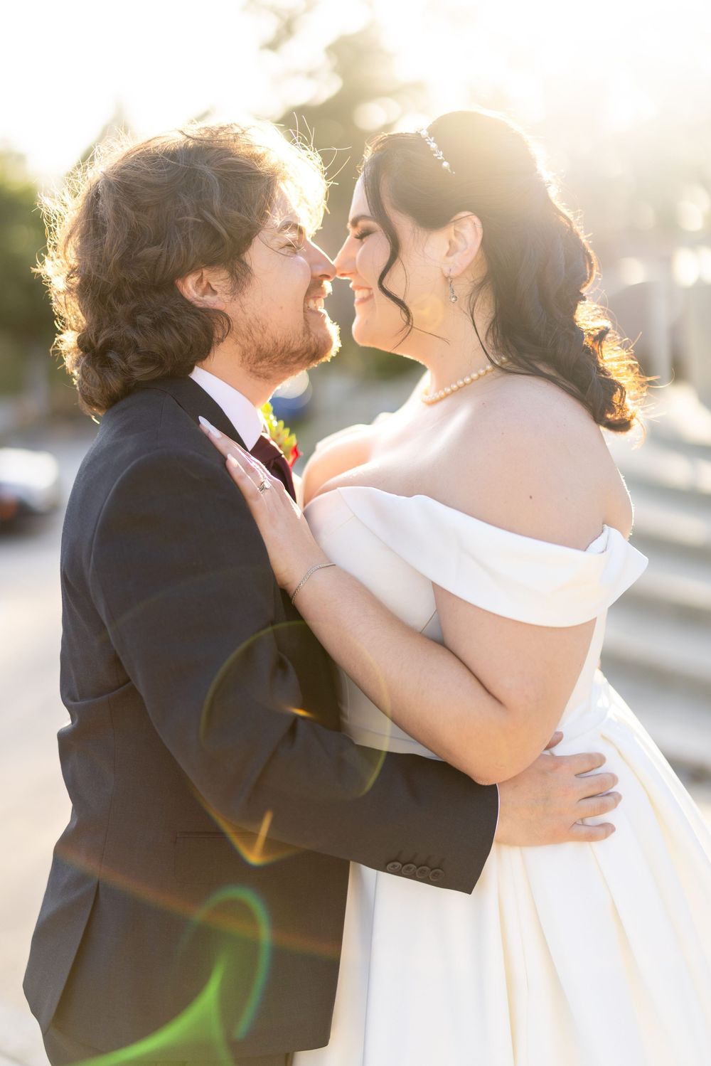 Golden sunlit wedding portrait with lens flare creating a dreamy romantic atmosphere.