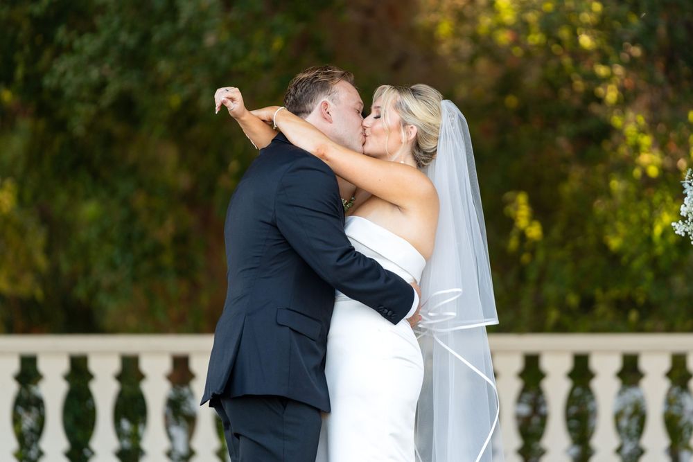 A wedding couple shares intimate moments on their special day in a garden setting during sunset.