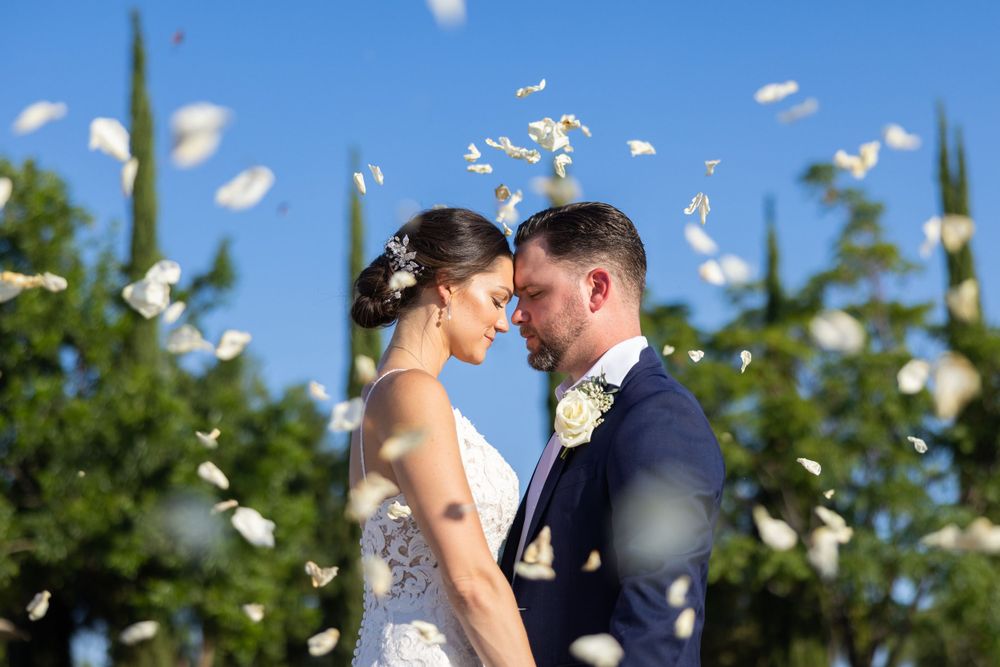 Flower petals fall around a couple during an intimate outdoor wedding moment.