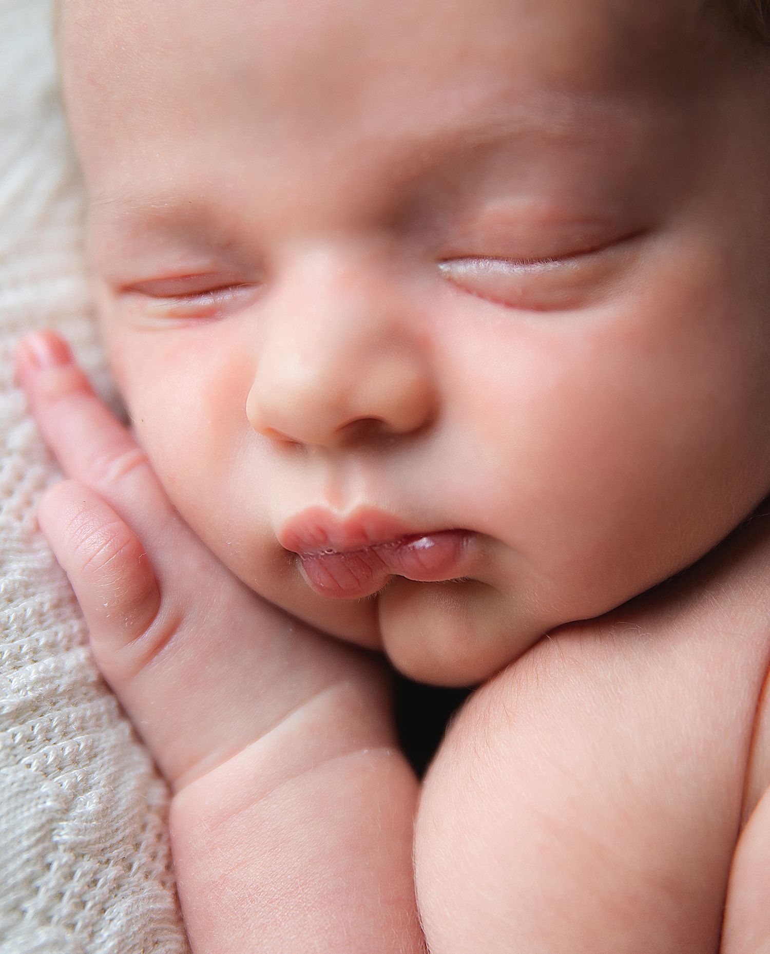 Close-up sequence of a sleeping baby's nose and mouth details in soft, dreamy lighting. During a newborn photoshoot in London