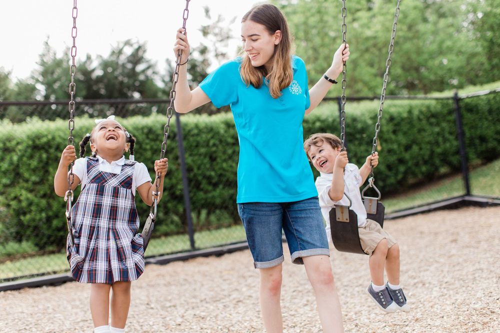 Three people having fun swinging together at a playground on a sunny day.