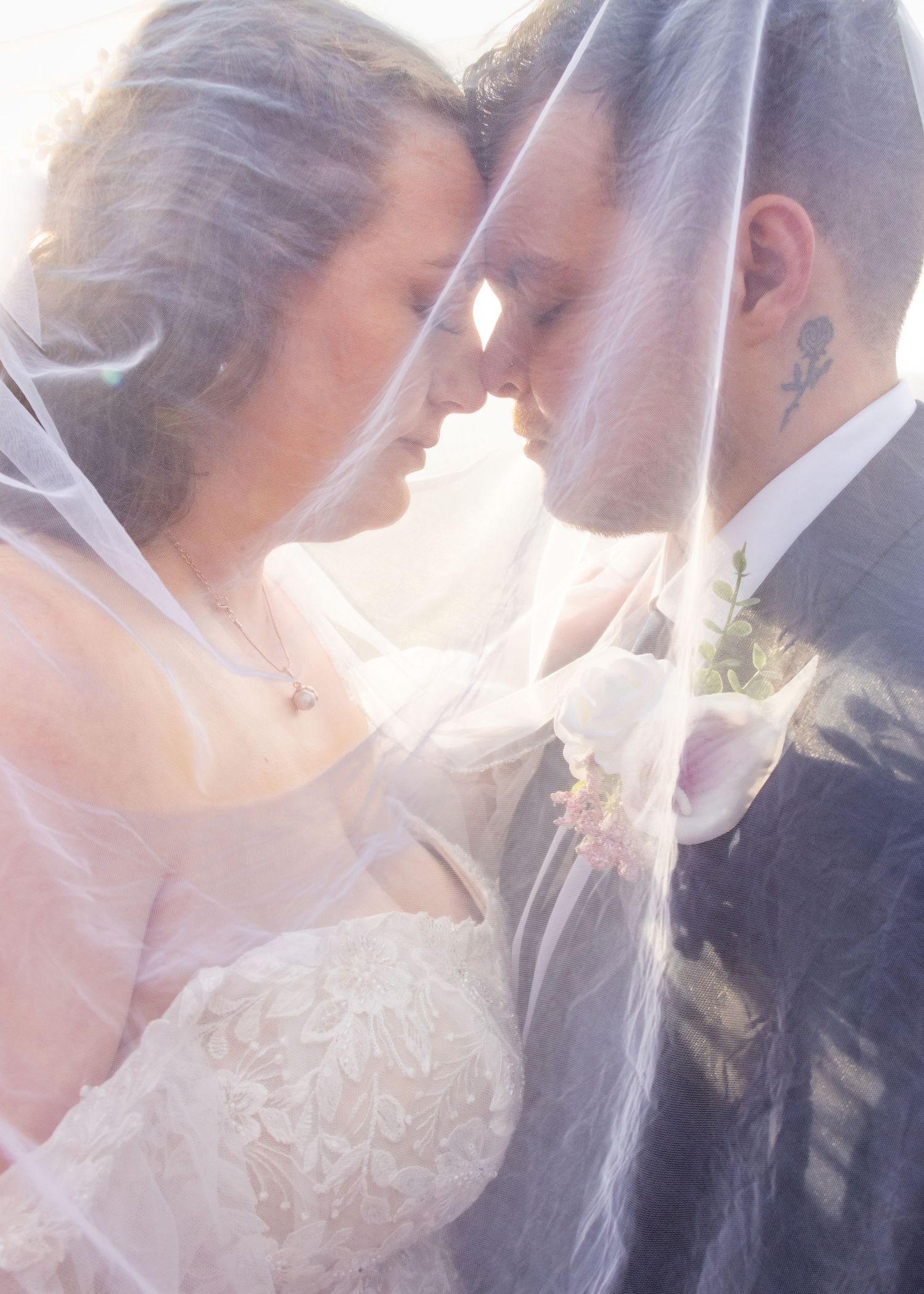 Romantic wedding couple silhouette with sunlit veil.