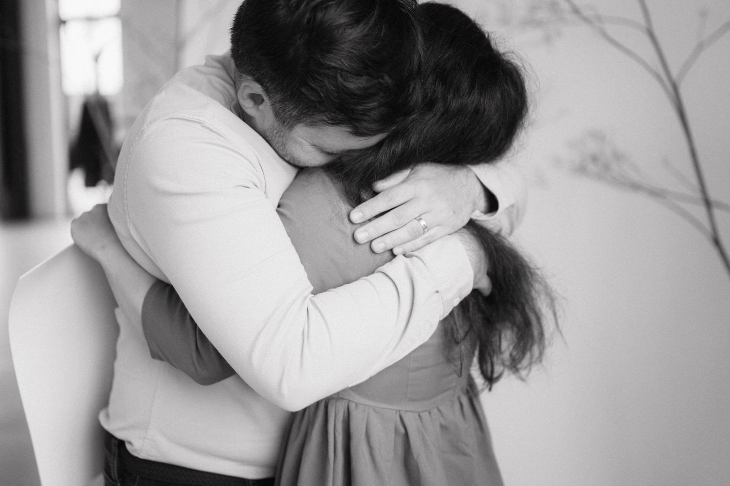 A tender black and white photograph captures an intimate embrace between two people in a gentle moment.