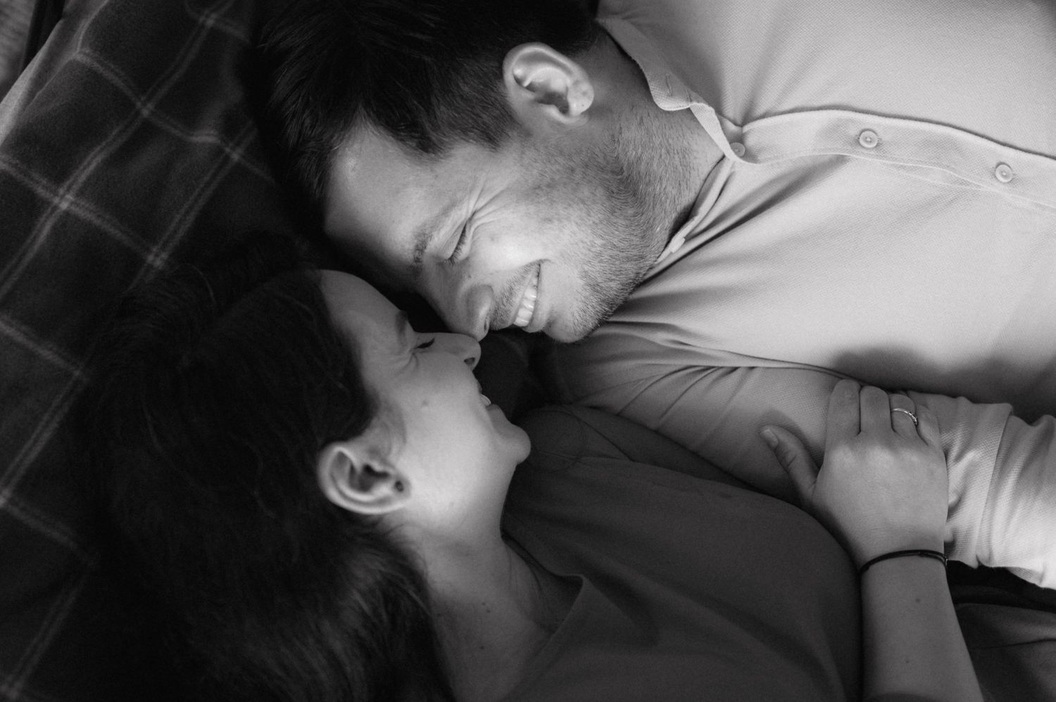 A black and white intimate portrait of a couple lying close together and sharing a tender romantic moment.