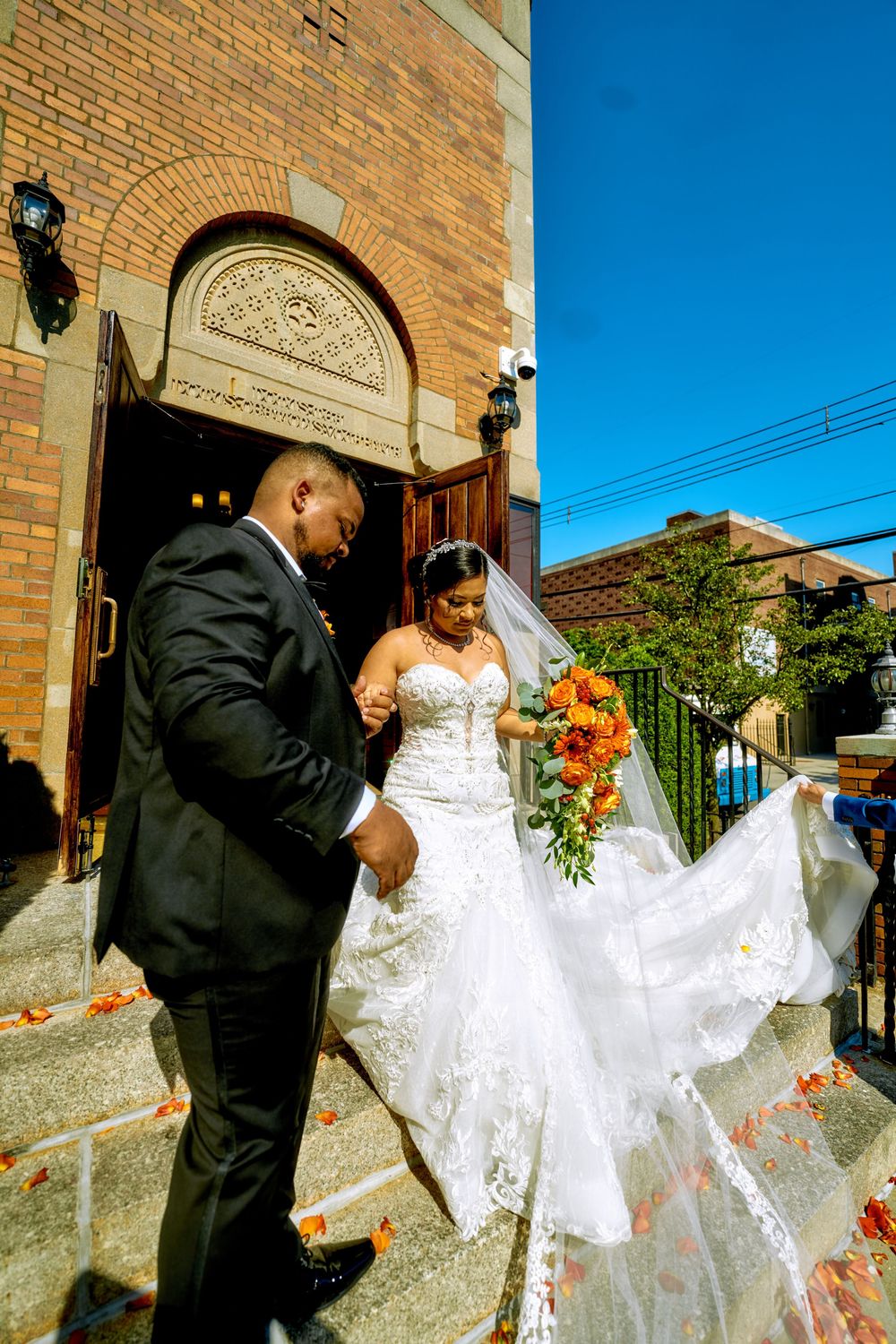 A joyful moment on church steps with billowing white wedding dress and autumn-themed bouquet.