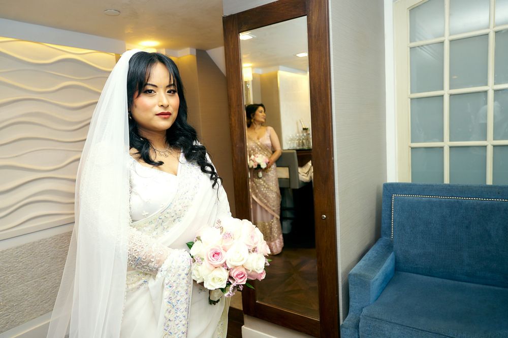 Bride in white dress with veil poses near modern wave-textured walls.