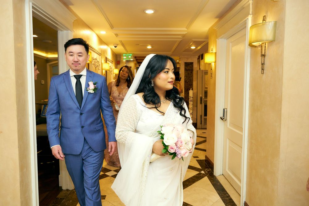 A couple walking down a luxurious hotel hallway during their wedding celebration.