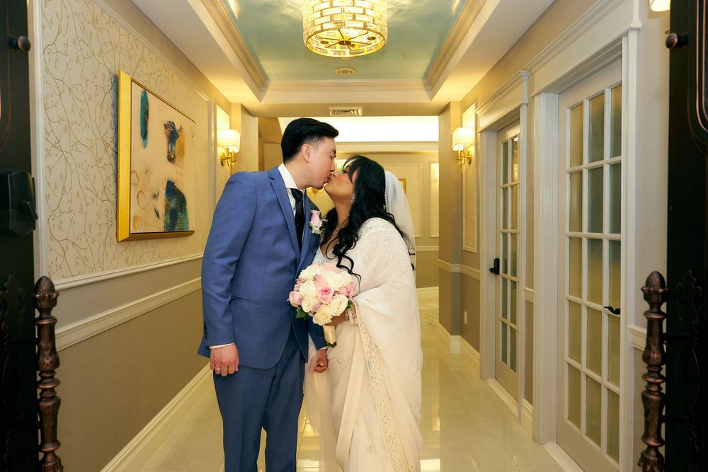 A tender moment shared in an elegant hallway with cream walls and chandelier lighting. at Jericho Terrace