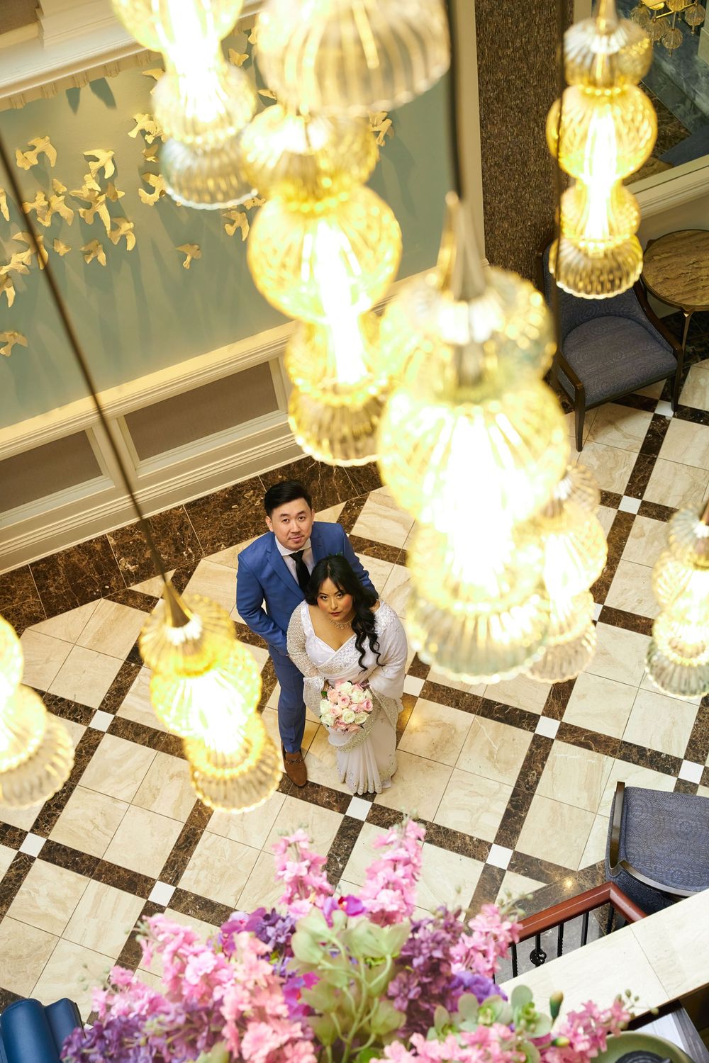 An overhead view of a couple beneath ornate glass chandeliers on a patterned marble floor. at Jericho Terrace