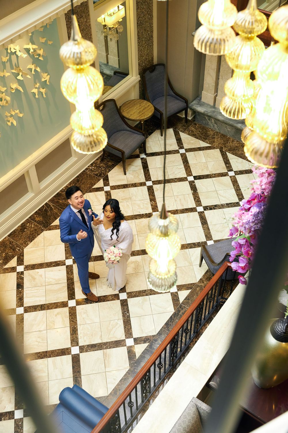 A bird's eye view of a couple standing on geometric marble flooring under glowing pendant lights. at Jericho Terrace