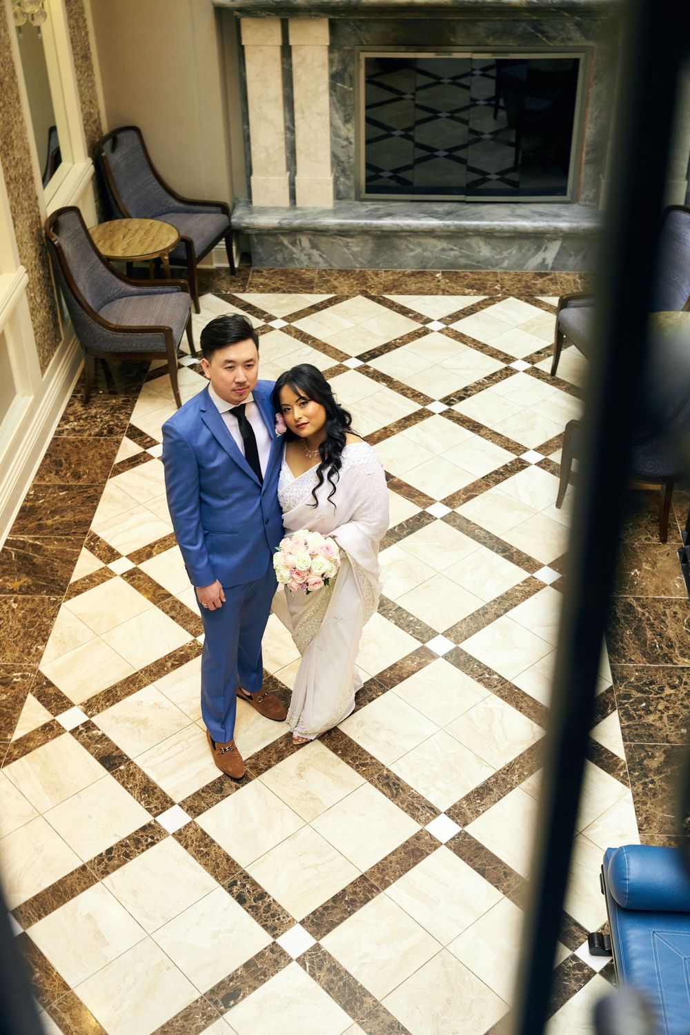 A high-angle shot of a couple on diamond-patterned marble flooring near a fireplace. at Jericho Terrace