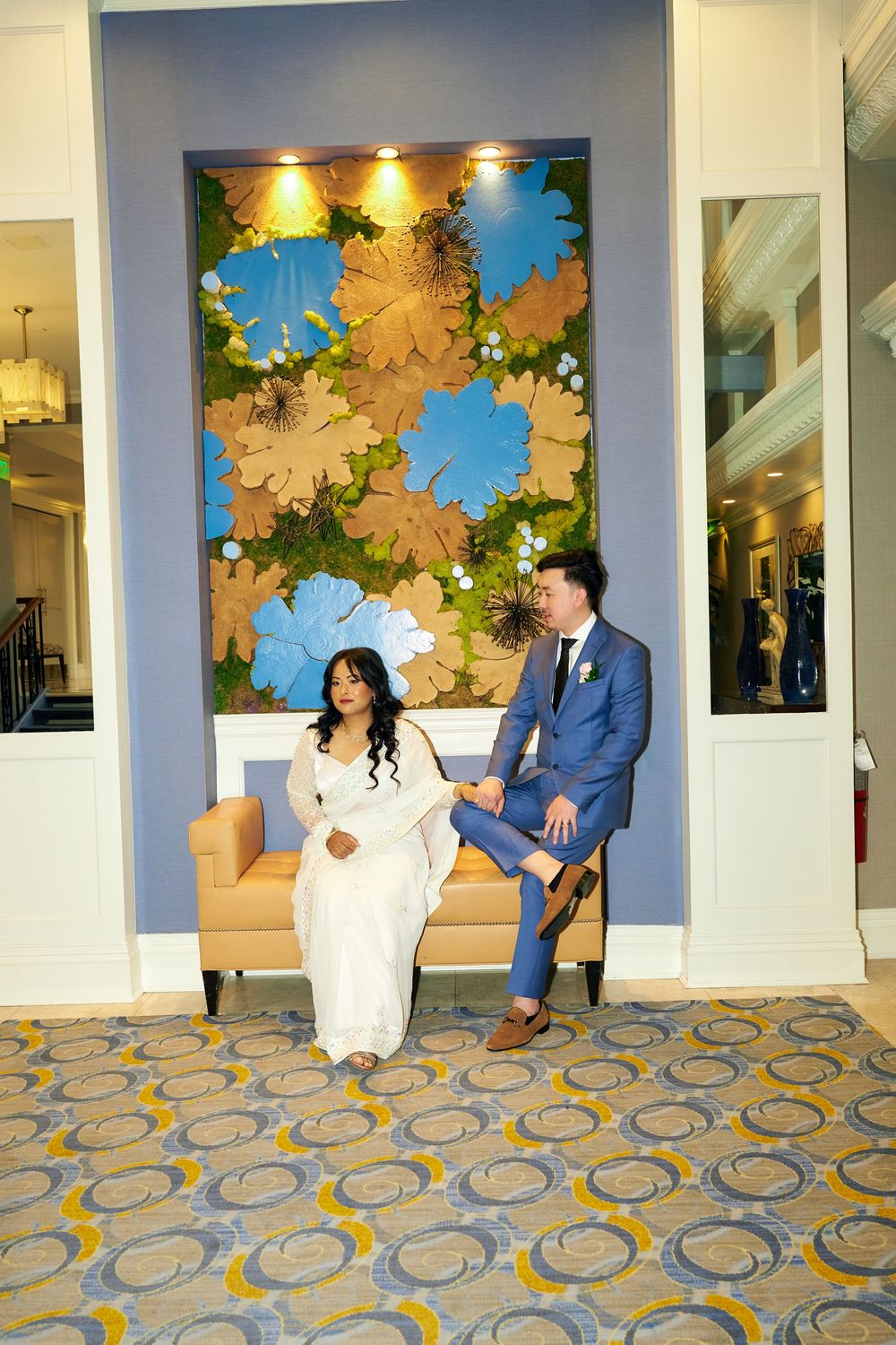 A couple seated beneath colorful wall art in a hotel lobby with patterned carpet. at Jericho Terrace