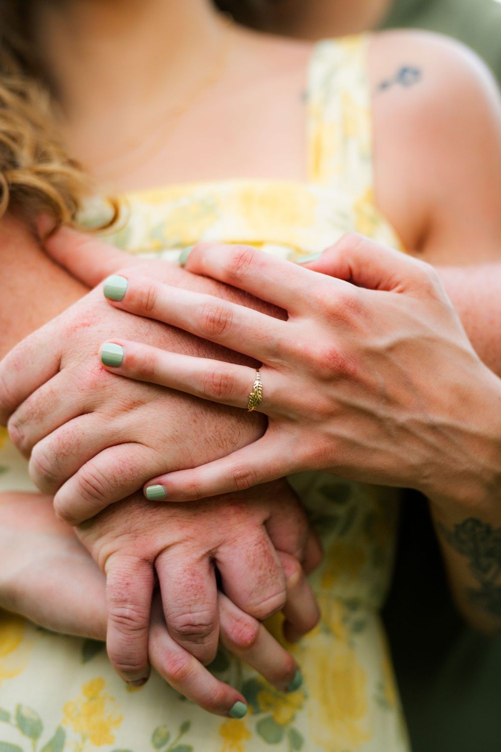 A romantic couple embraces and kisses in a lush garden setting with wildflowers and tall trees at sunset for their engagement photos