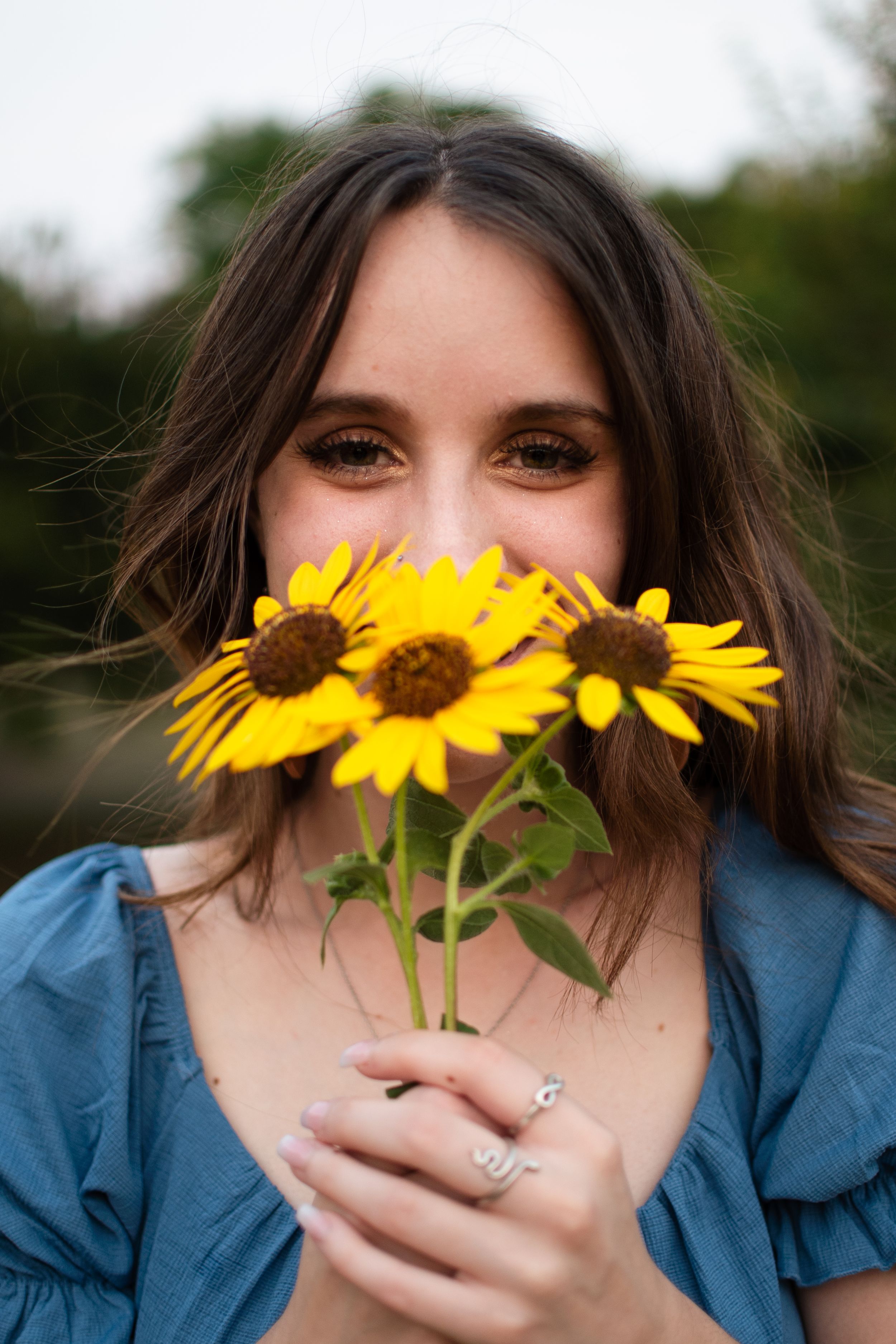 A creative portrait featuring bright yellow sunflowers against a natural outdoor background. Fort Worth