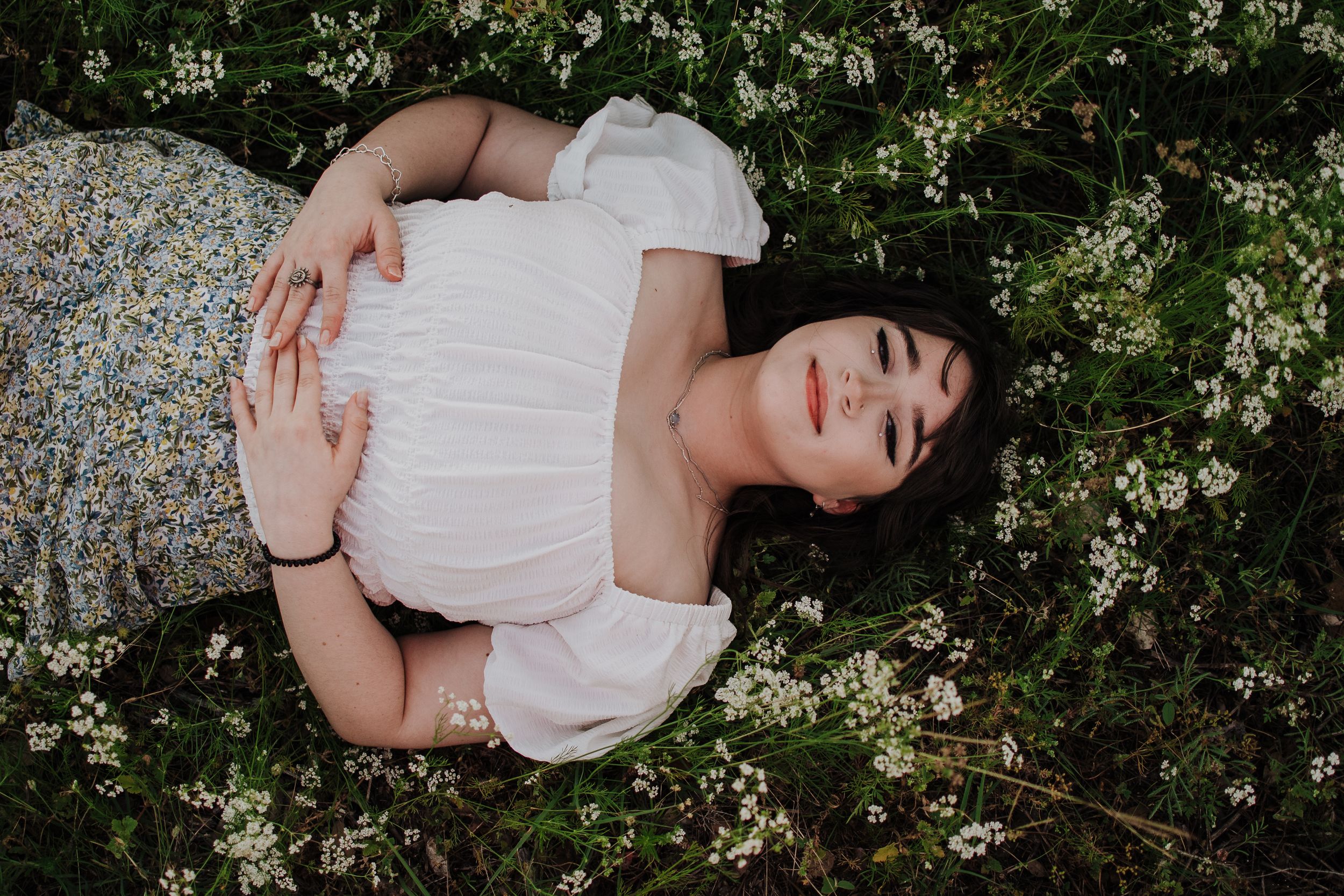 A spring maternity photo surrounded by delicate white blossoming flowers. Tandy Hills SEnior session