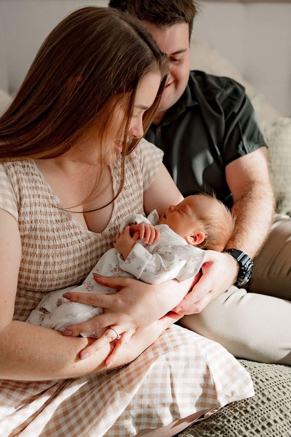 A parent cradles a sleeping baby while sitting on a couch in a series of connected images.