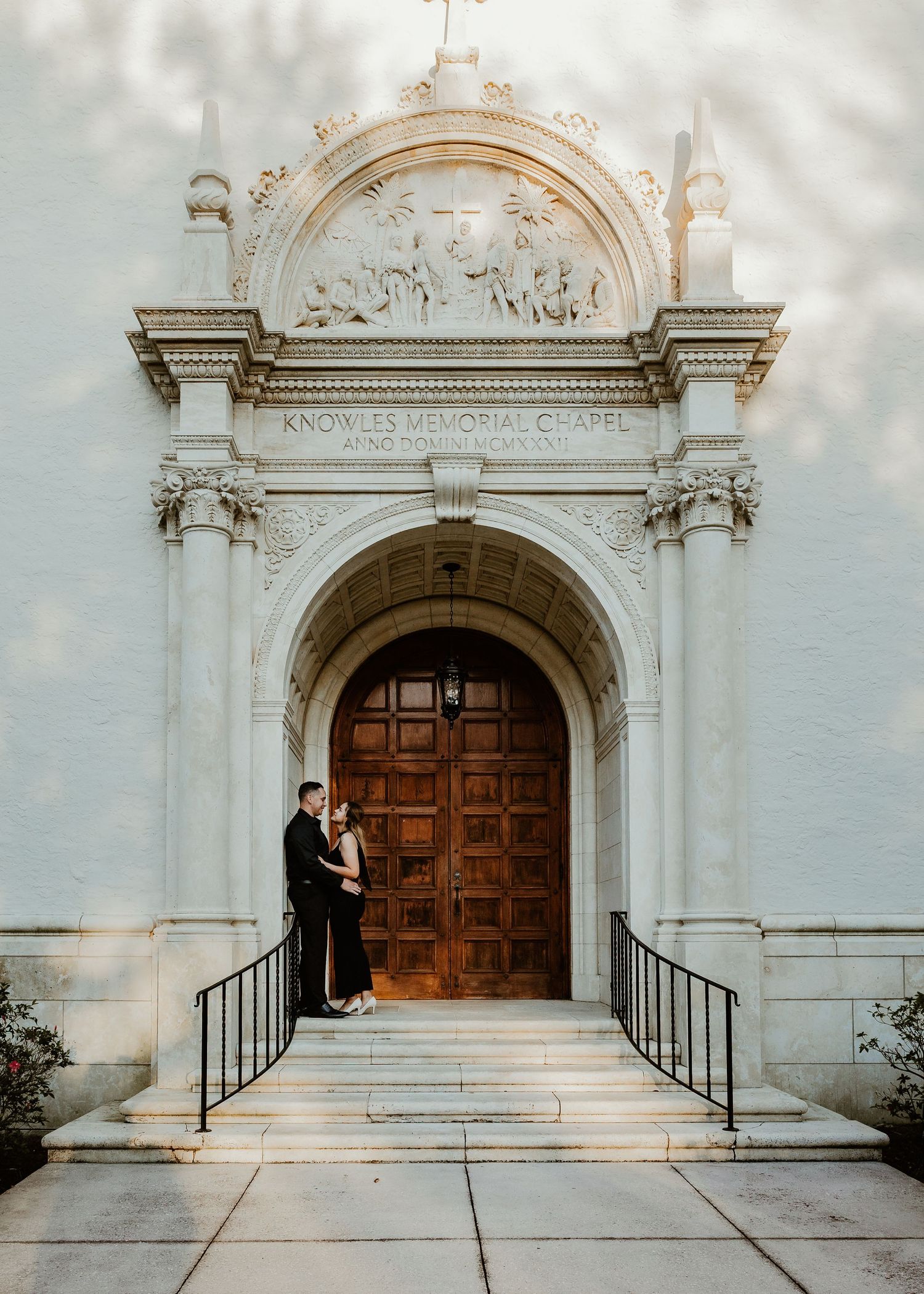 A stately church entrance with ornate white stone archway and wooden double doors.