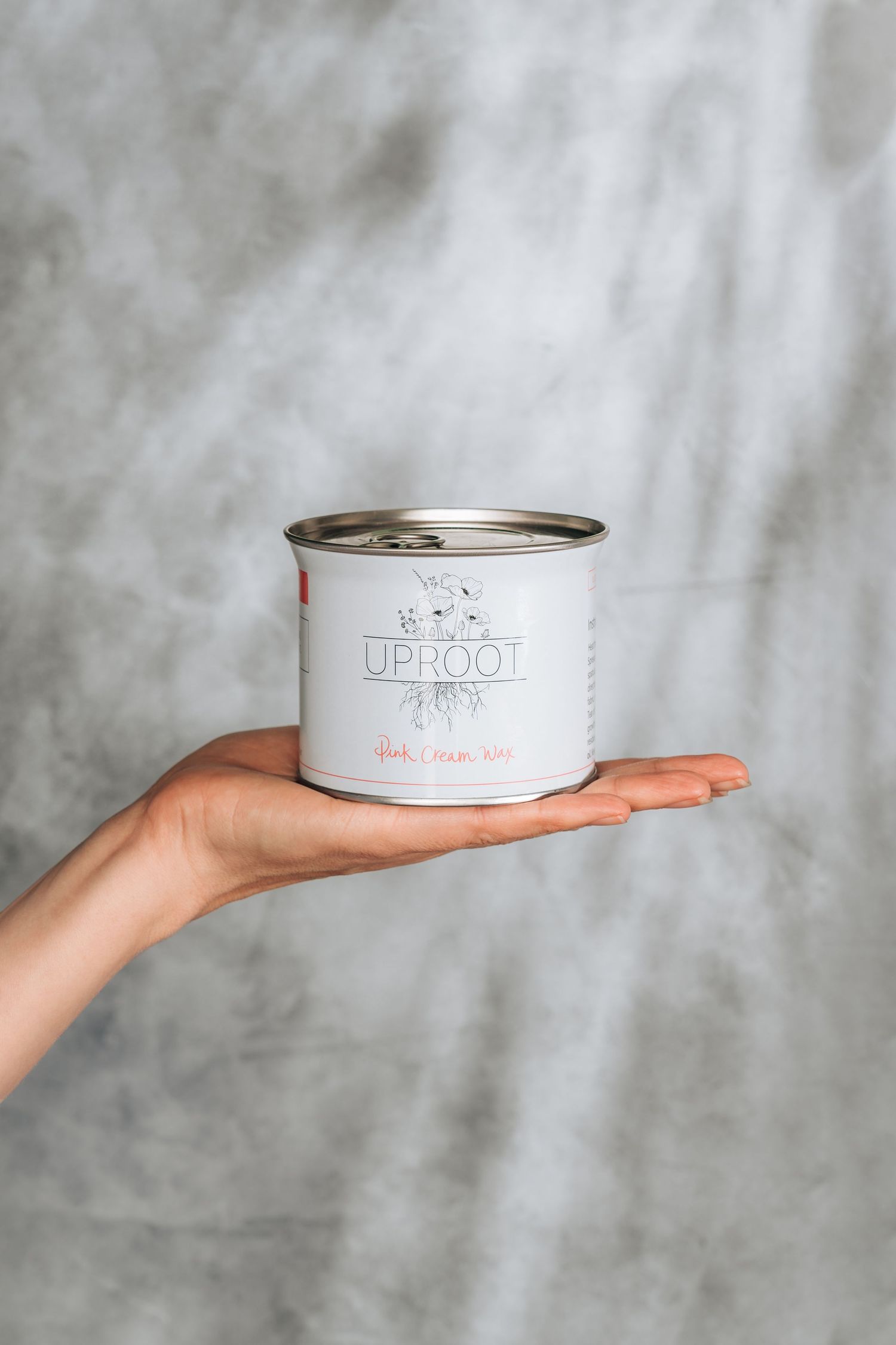 Hand holding a white minimalist cat food can against a gray textured background in a progression of three poses.