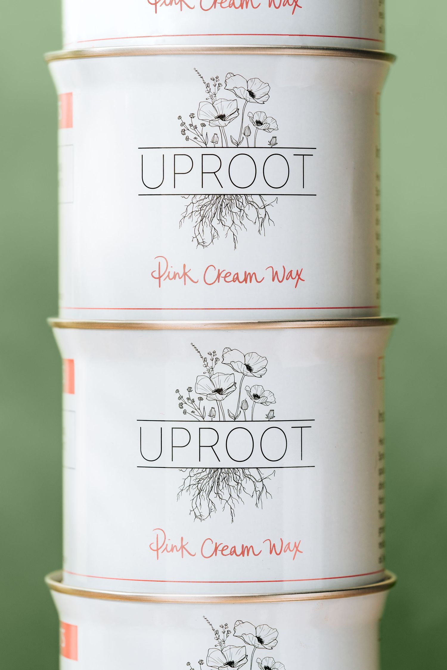 Stacked white cylindrical containers branded as Uproot Pink Cream Wax on wooden surface.