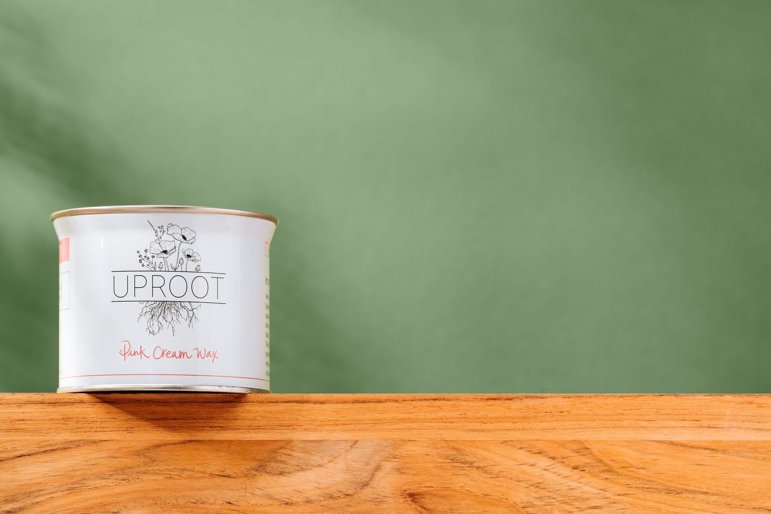 White paint can on wooden surface against green background.