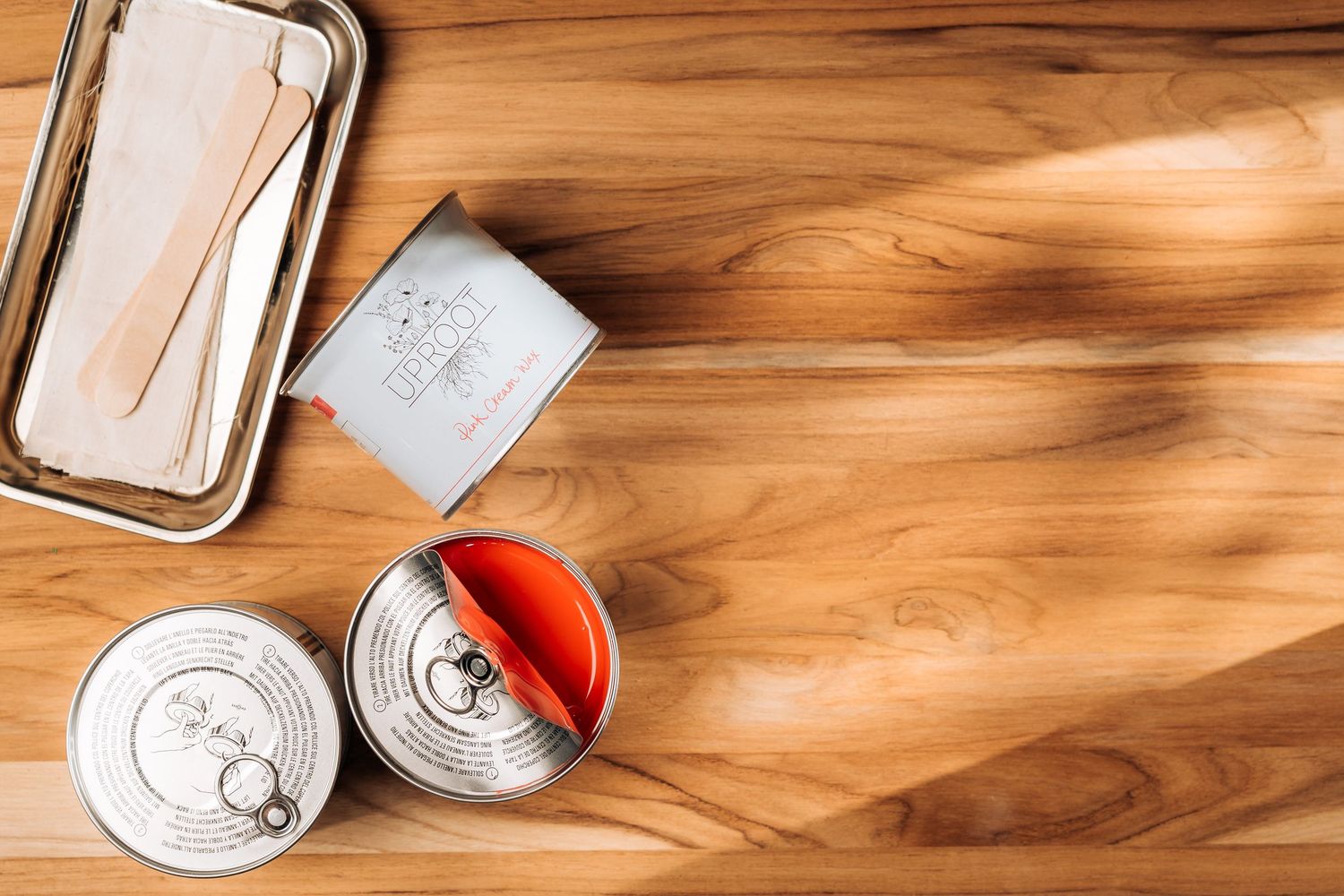 Empty metal storage tins and silver tray arranged on a wooden surface with dramatic side lighting.