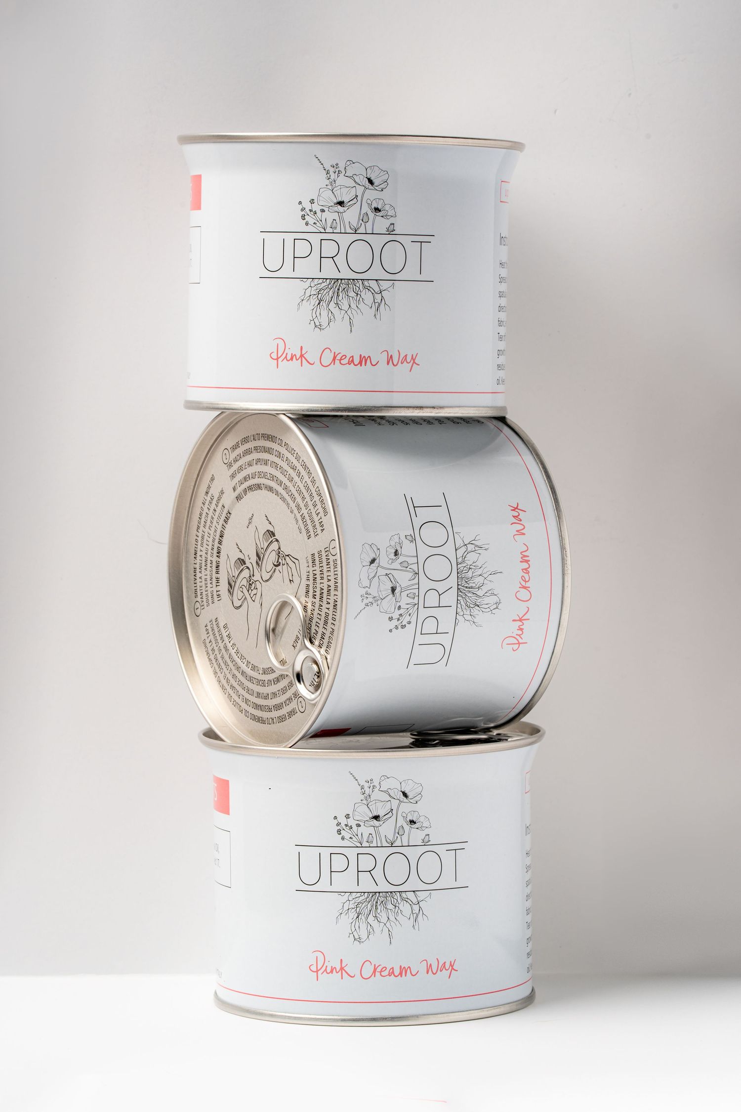 Three stacked white cylindrical cans with minimalist Uproot branding and root design illustrations against a light background.