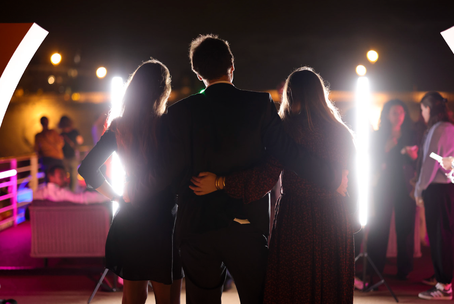 Silhouetted figures stand against bright stage lights during an event performance.