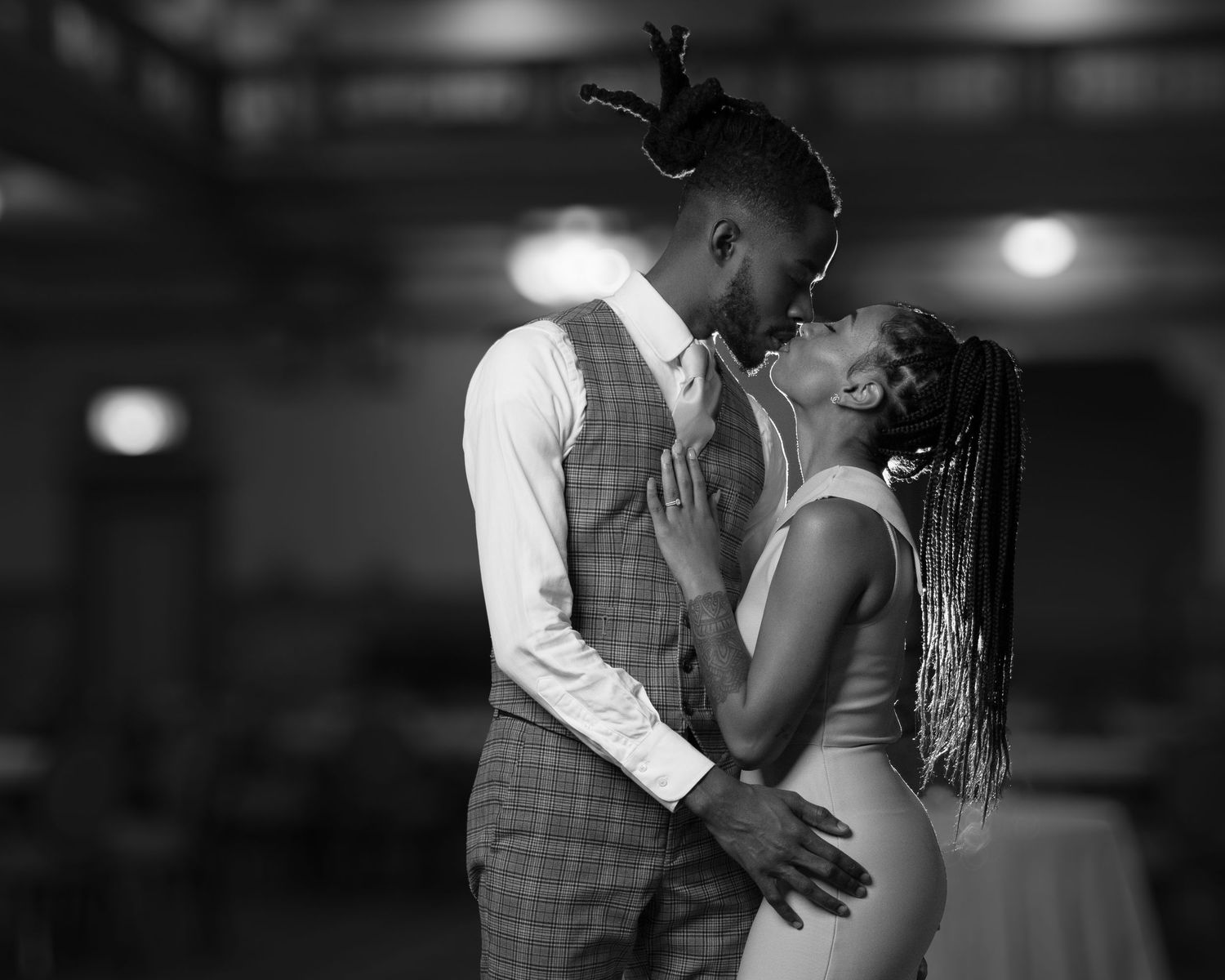 Black and white photo of a young couple kissing on stage with a light in the background