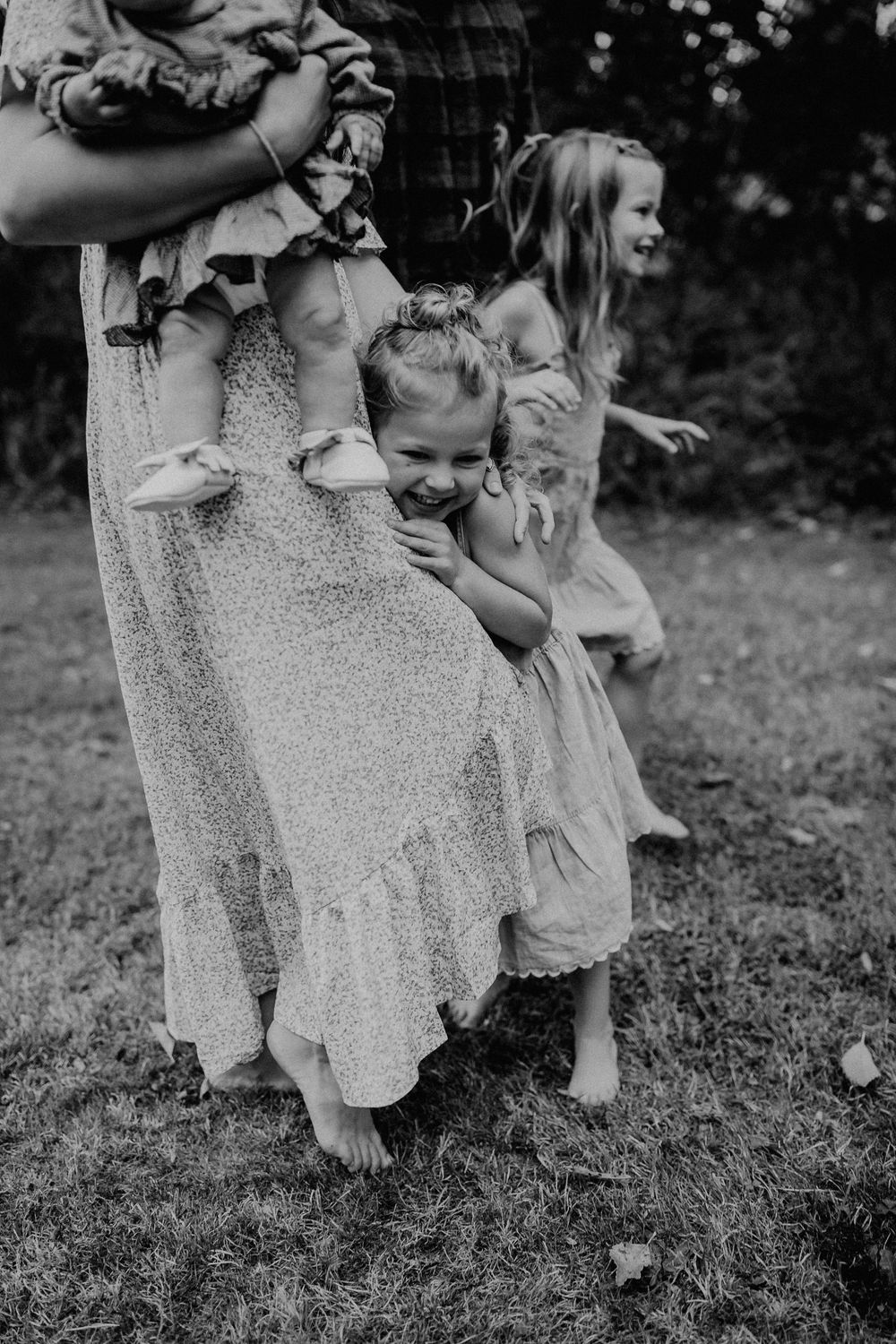 A tender family moment captured in black and white as they play together on grassy ground.